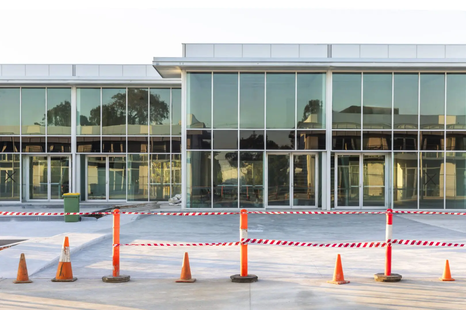 A building with orange cones around it and a red barrier.