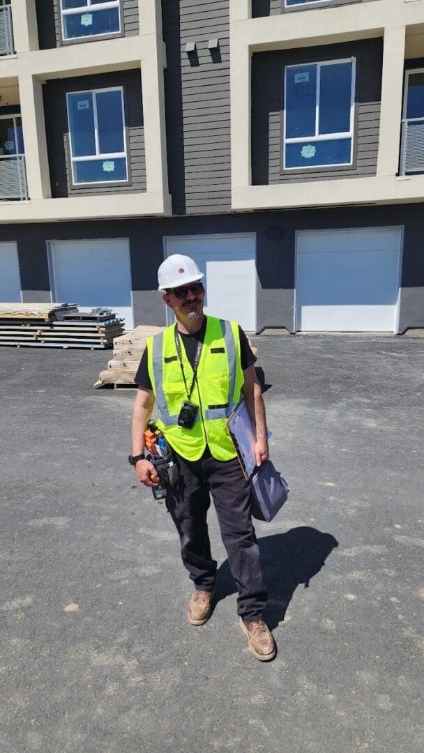 A man in yellow vest and hard hat standing on street.